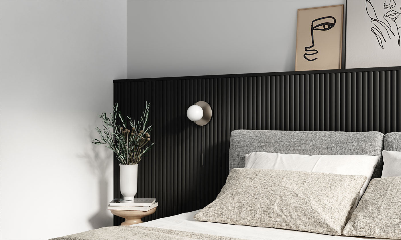 A modern bedroom showcasing wide fluted paintable wall panels in black, with a stylish grey bed and a simple white vase with greenery on a bedside table.