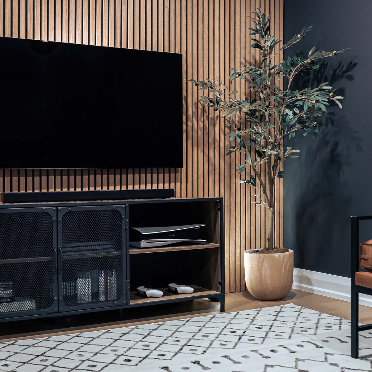 Stylish home office with a large wall-mounted TV, wooden slat accent wall, black metal storage unit, and a potted plant, featuring contemporary home office ideas.