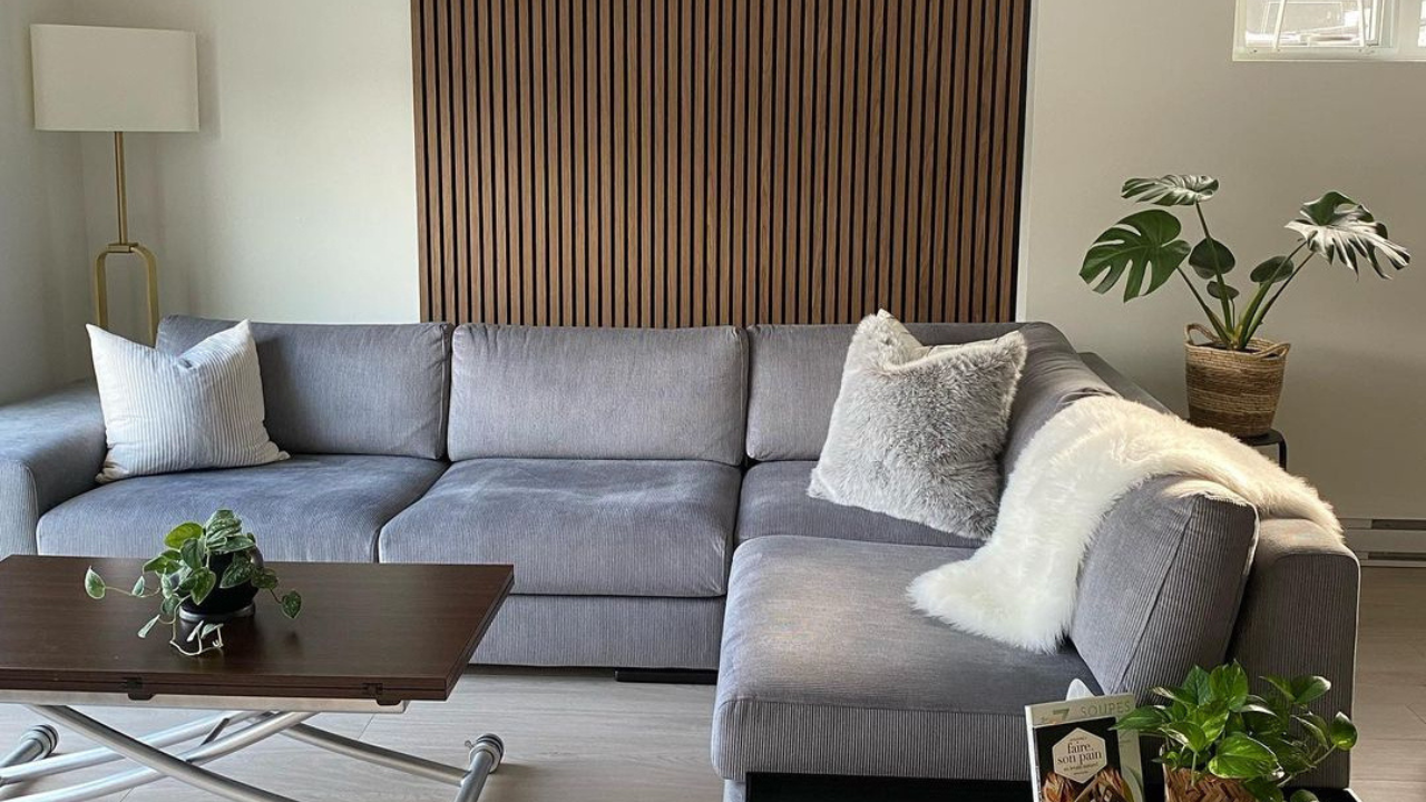 Modern living room with a gray sectional sofa and wall panel decor for living room.