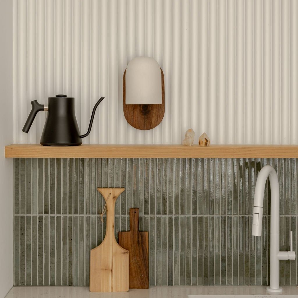 Modern kitchen with slim green tile backsplash and white fluted wall paneling above sink