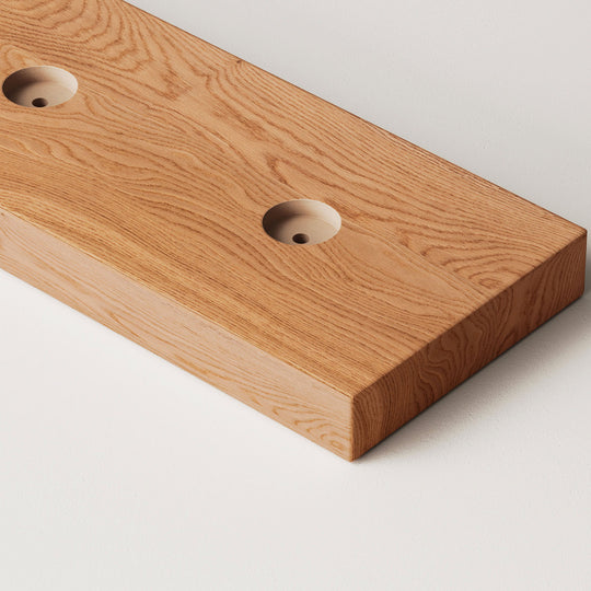 closeup image of wood slat divider floor base with pre-drilled holes in golden oak