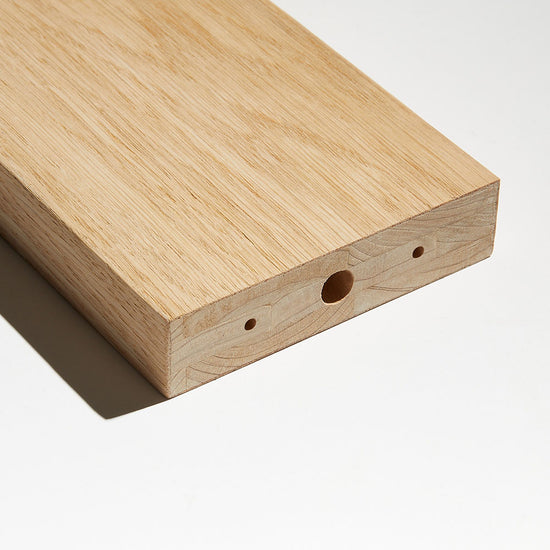 closeup image of a white oak wood slat with pre-drilled holes for room divider hardware