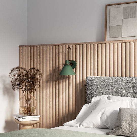 Bedroom with fluted wood headboard, green wall lamp, and decorative elements.