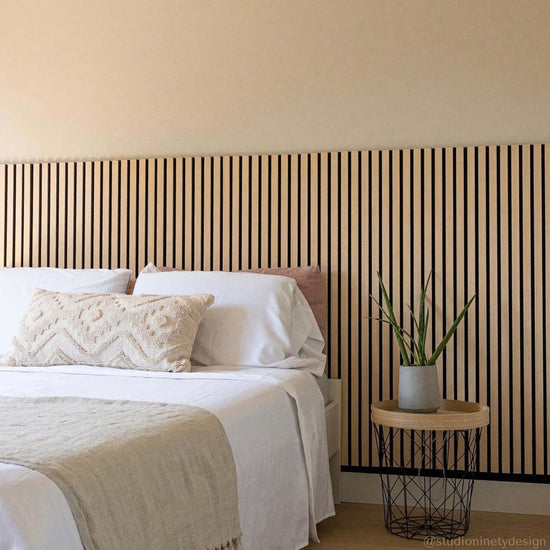 organic boho bedroom with neutral bedding and a white oak wood slat wall with oak flooring