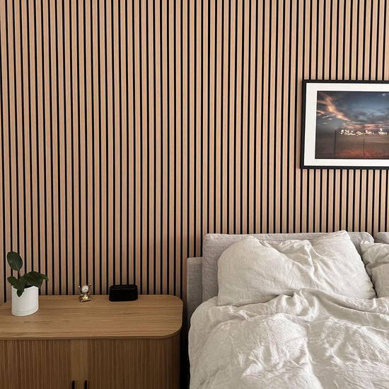 modern bedroom with white sheets framed art and a vertical wood slat wall behind the bed